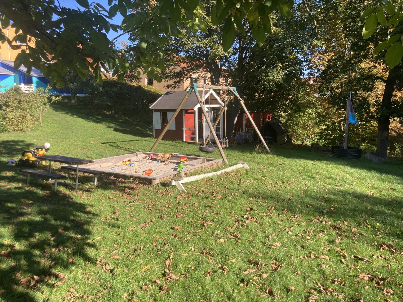 Legeplads med sandkasse, gynger, legehus og lille piratskib.